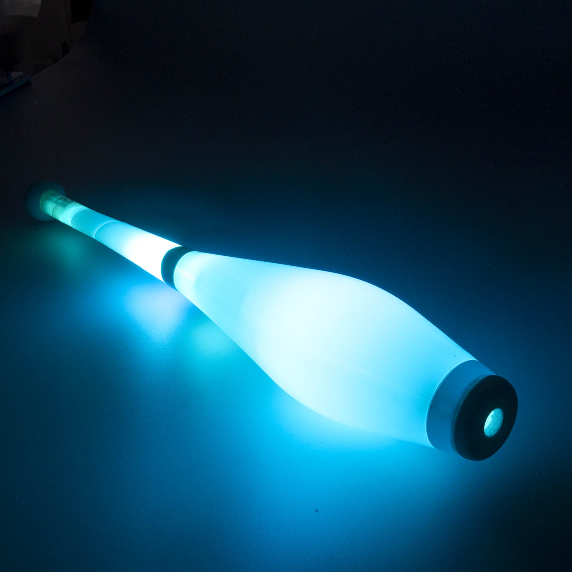 Nebula 3 LED juggling club laying glowing blue on a dark background