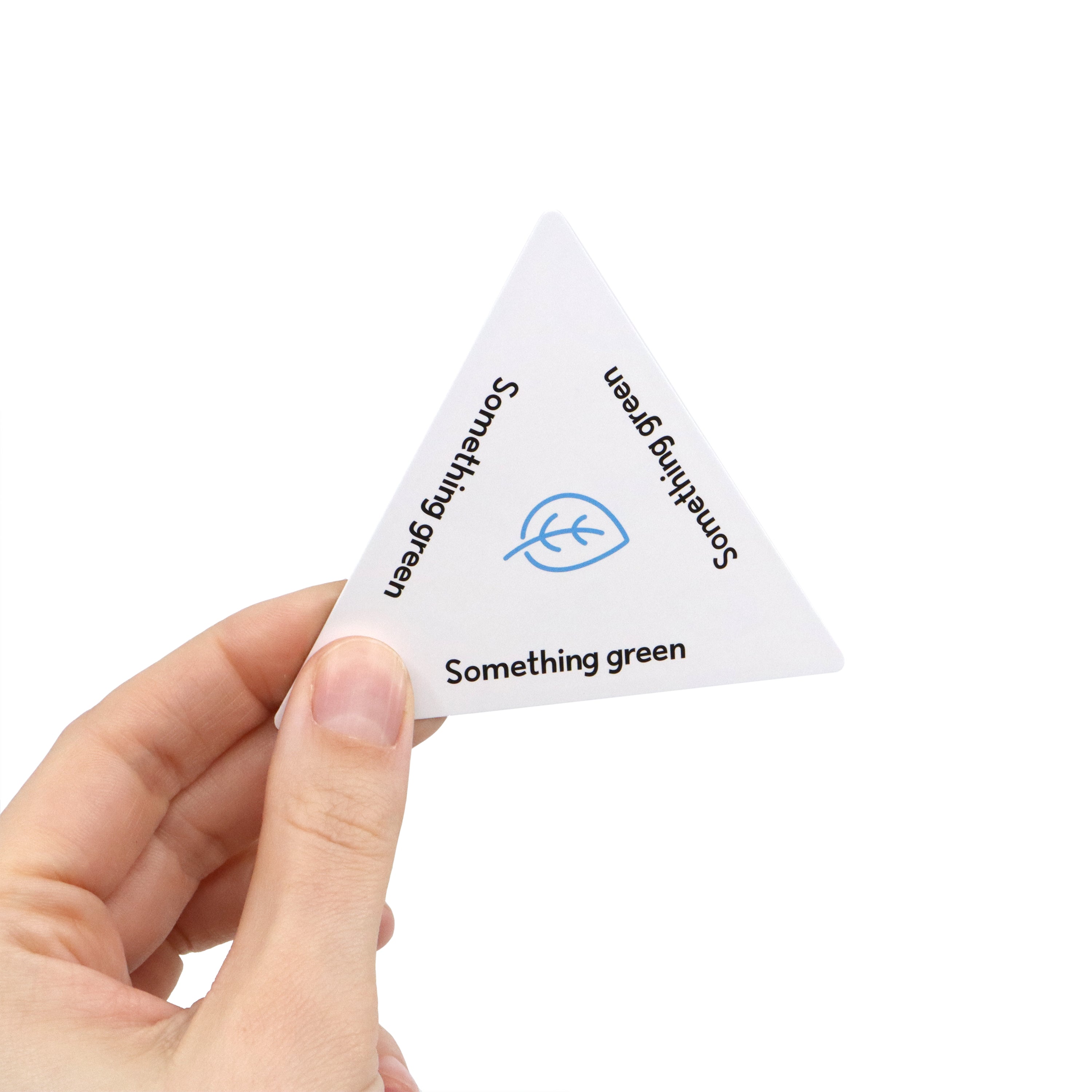 Hand holding a triangular white card with 'Something green' text on a white background