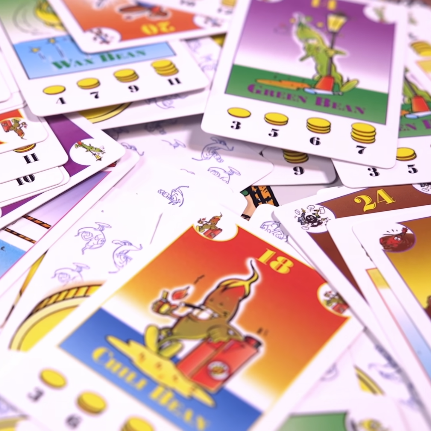 Colorful playing cards with cartoon illustrations scattered on a surface.