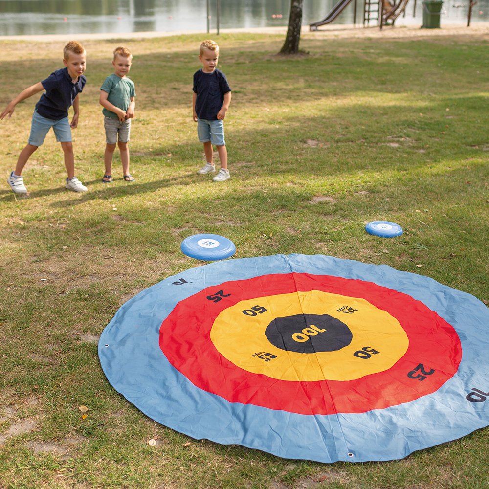 Children playing with a large target mat on grass 